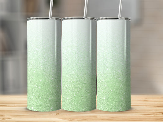 Three glitter tumblers with green and white ombre gradient, on a wooden surface.