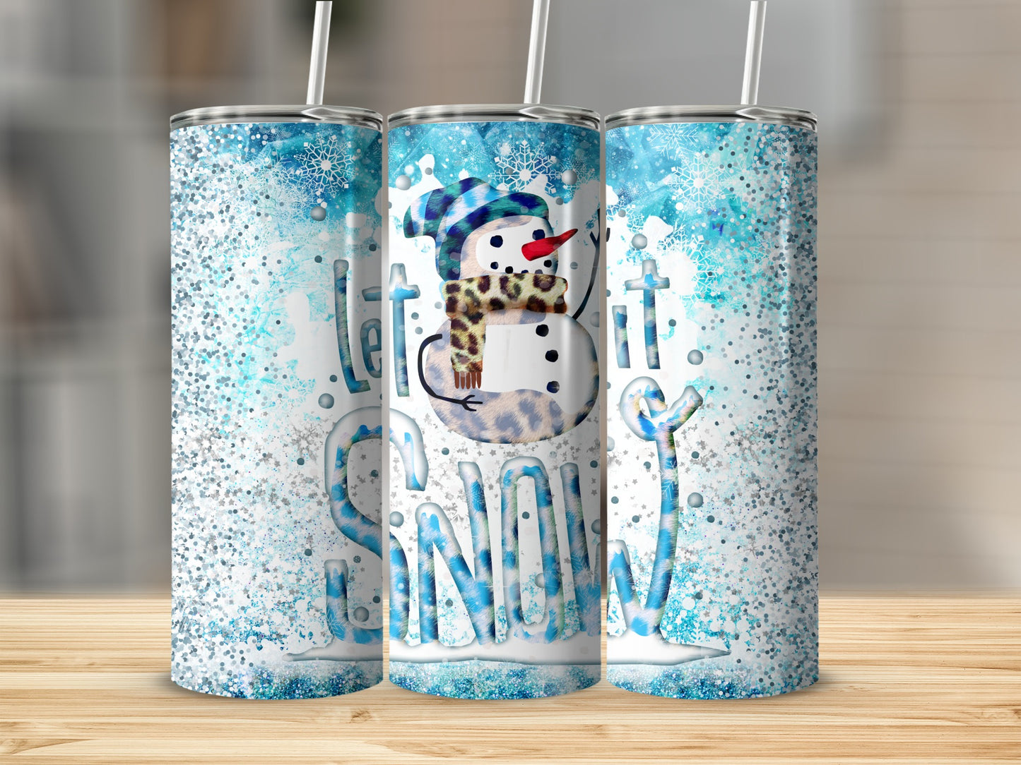Three tumblers with snowman and "Let it Snow" design on a wooden surface.