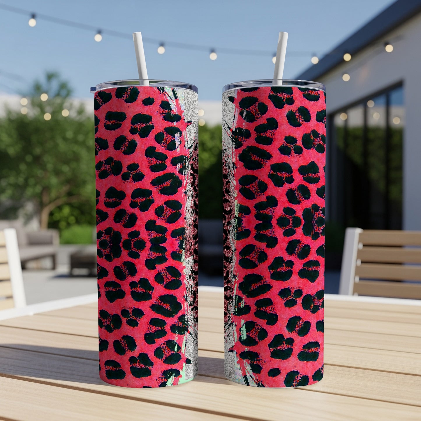 Two pink leopard print tumblers with black accents on a wooden table.