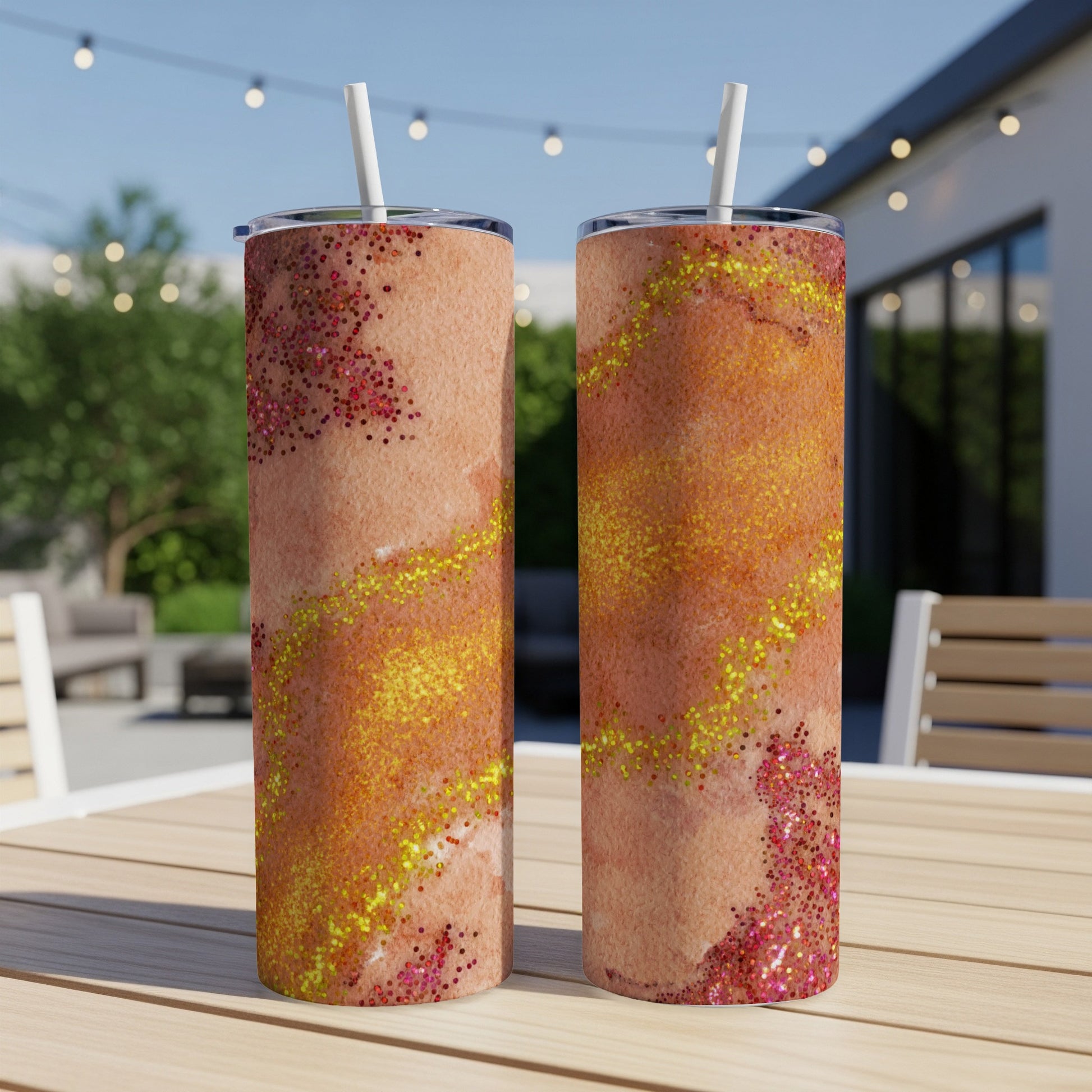 Two glitter-covered tumblers with marbled orange and pink designs on a table.