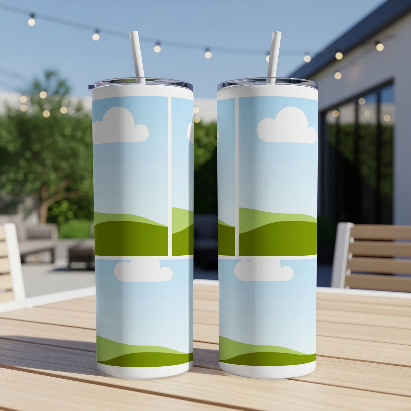 Two tumblers with a sky, cloud, and rolling green hills design on a table.