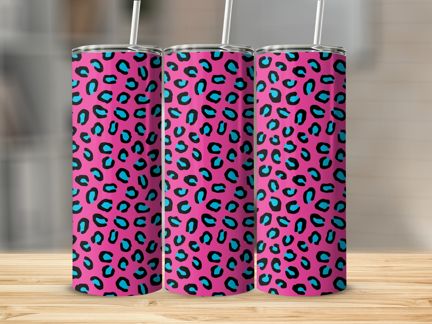 Three pink tumblers with a blue and black leopard print and white straws.