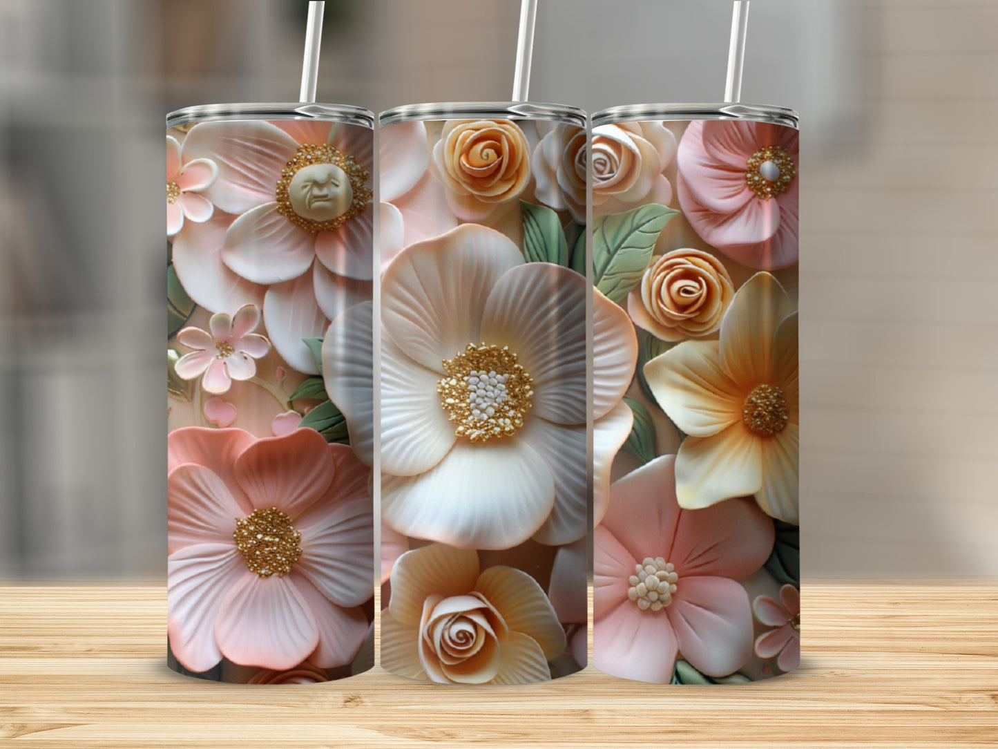 Three pastel floral tumblers with embossed detail and straws, displayed on a wooden surface.