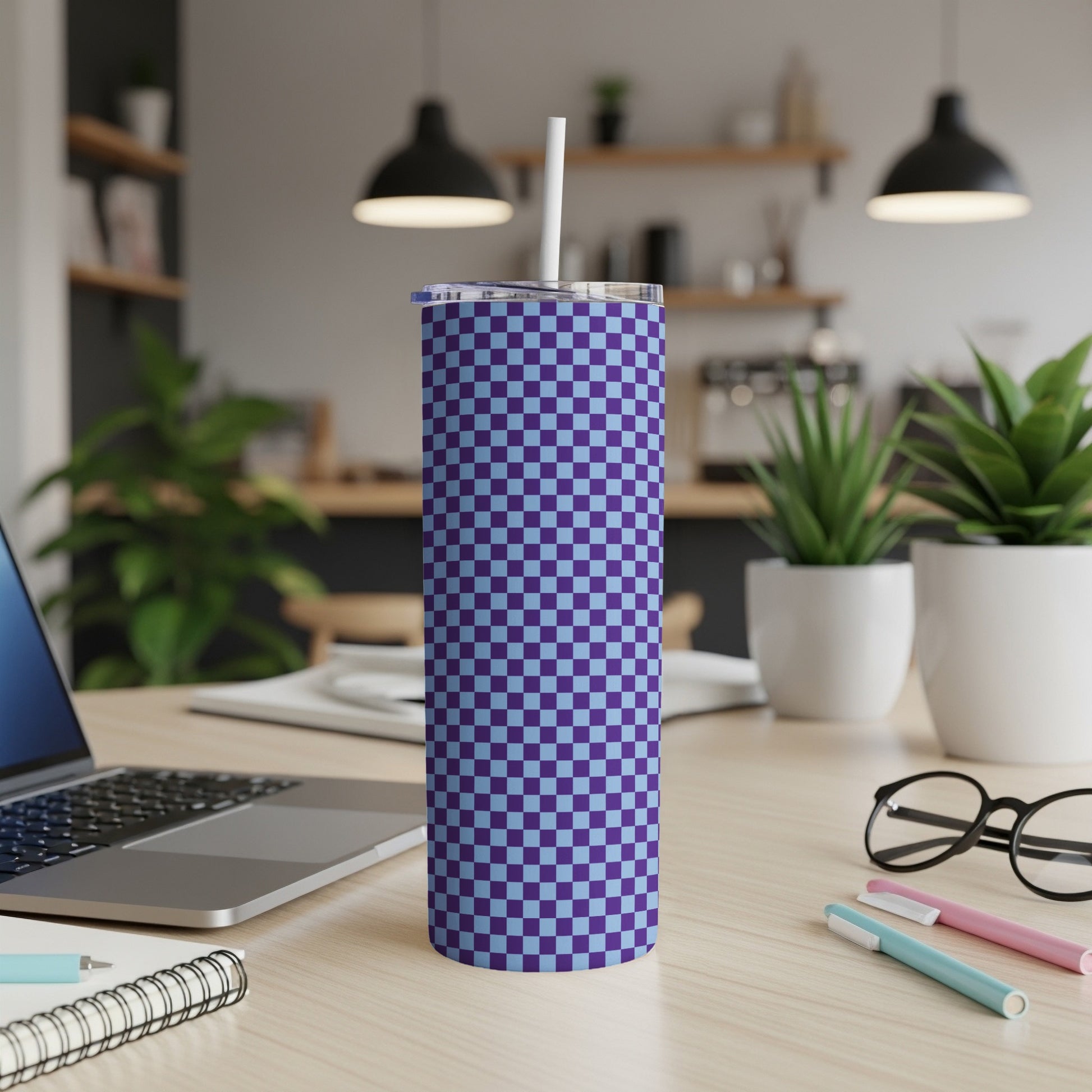 Purple and blue checkered tumbler with a straw on a desk.