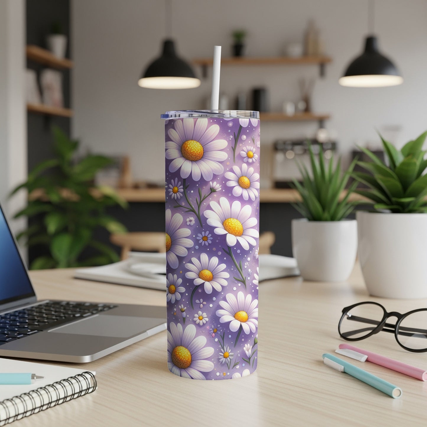 Purple tumbler with white and yellow daisies, straw, on a desk.