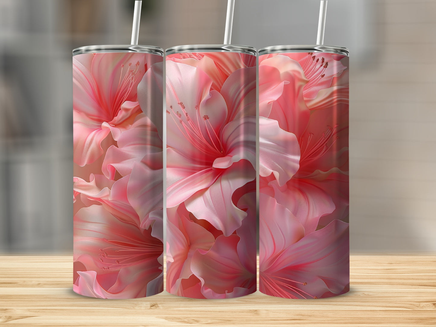 Three pink floral tumblers with straws on a wooden surface.