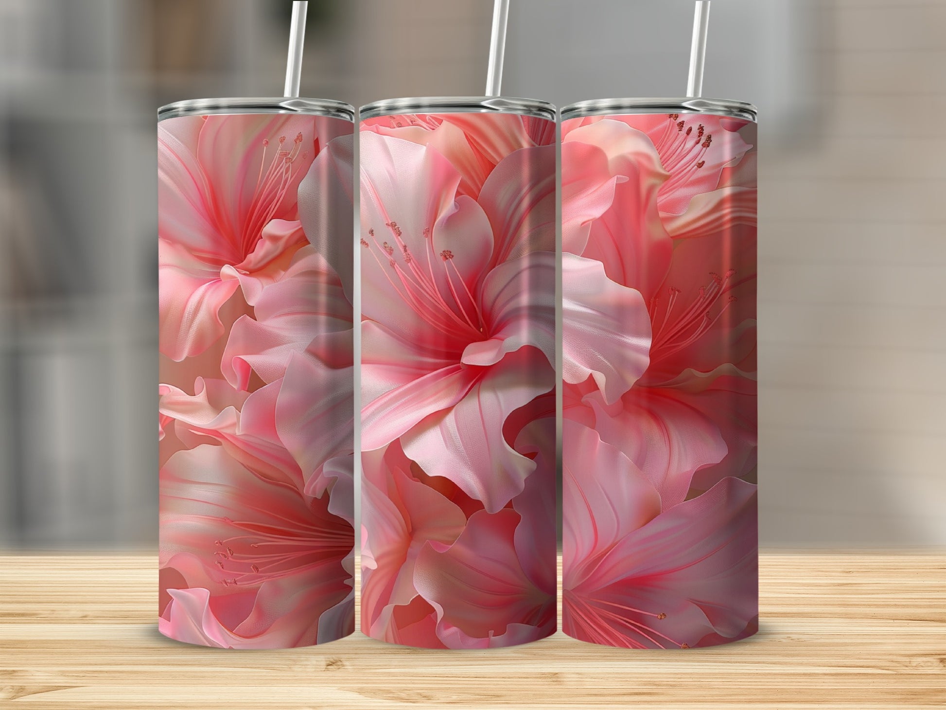 Three pink floral tumblers with straws on a wooden surface.