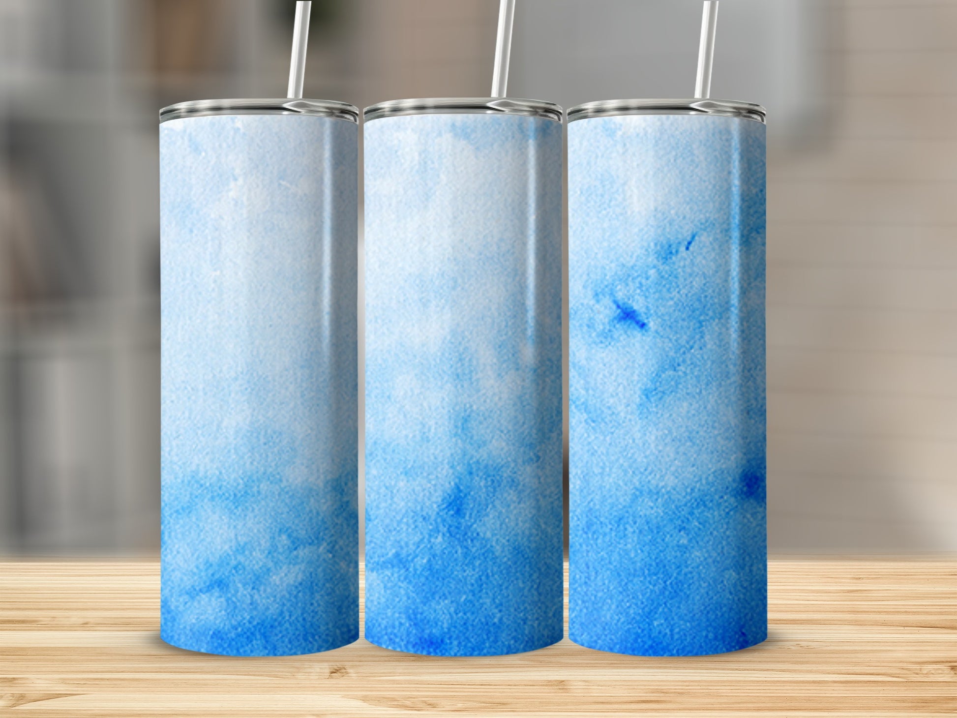 Three tumblers with a blue watercolor gradient and white straws.