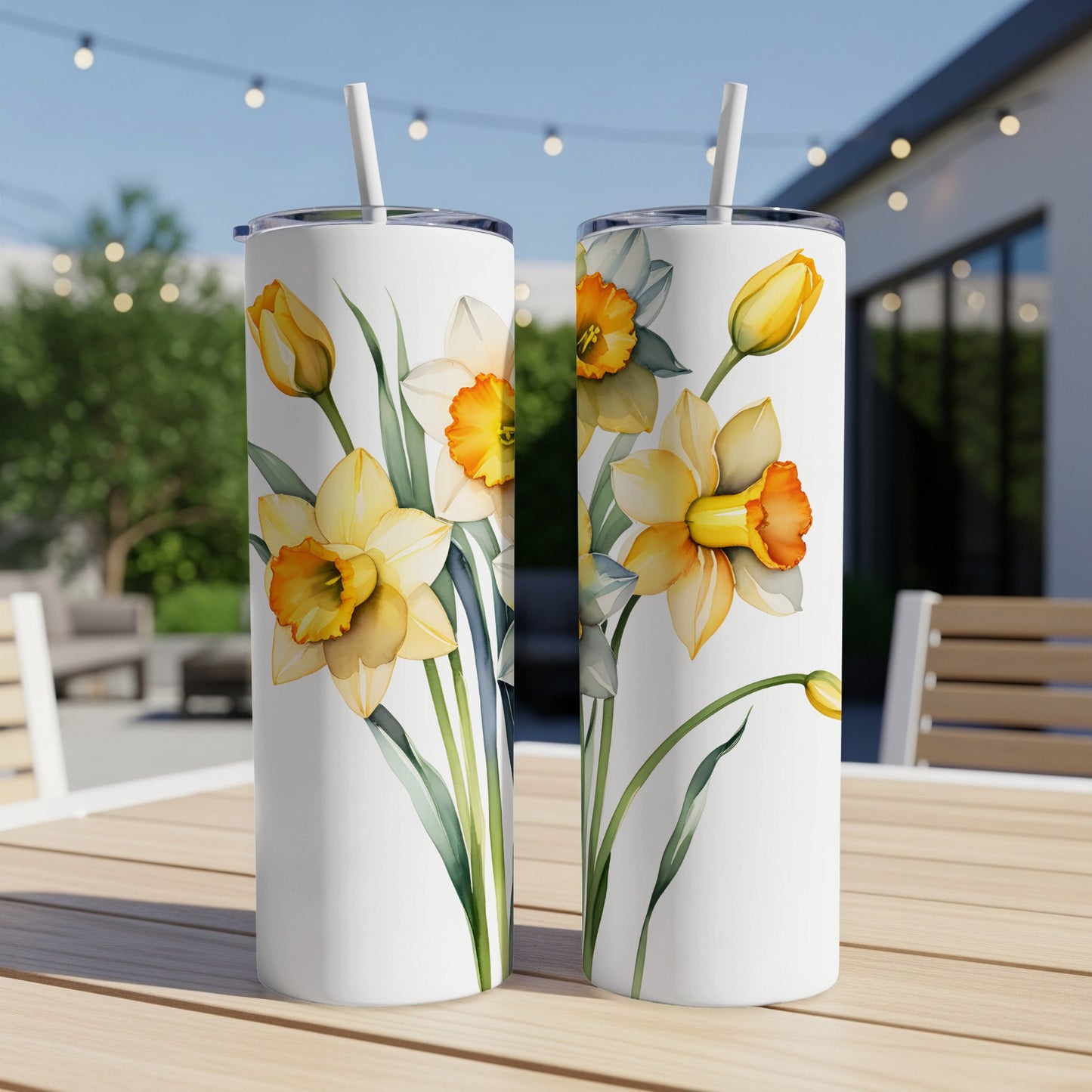 Two white tumblers with yellow and white daffodils illustration on a table.