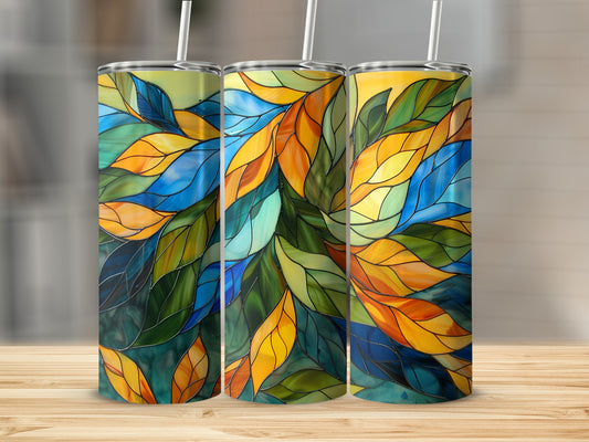 Three stained glass tumblers with colorful leaf patterns stand on a wooden surface.