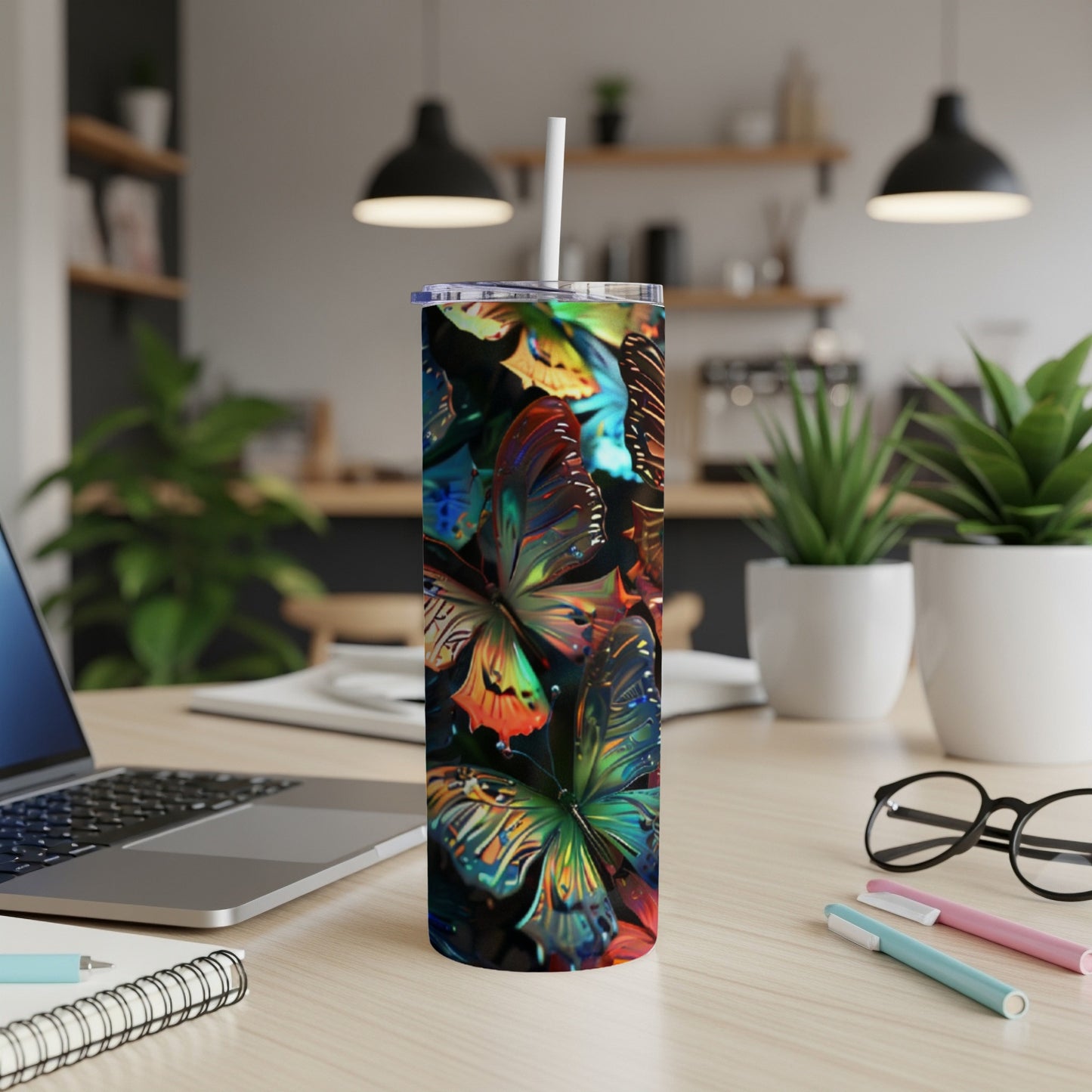 Tall tumbler with colorful butterfly pattern and straw on a desk.