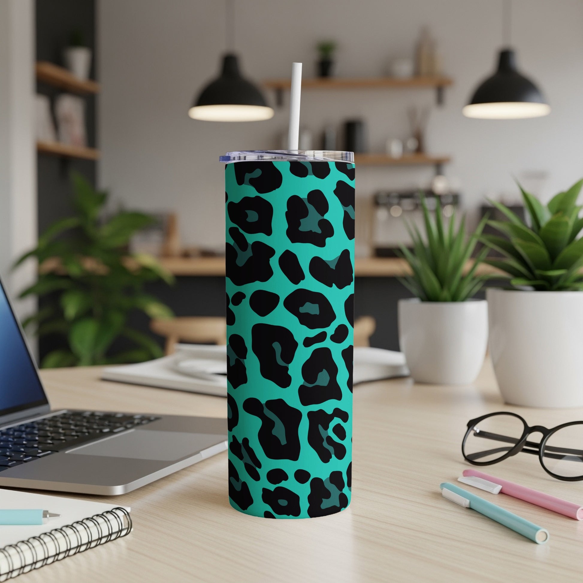 Turquoise tumbler with black leopard print and white straw on a desk.
