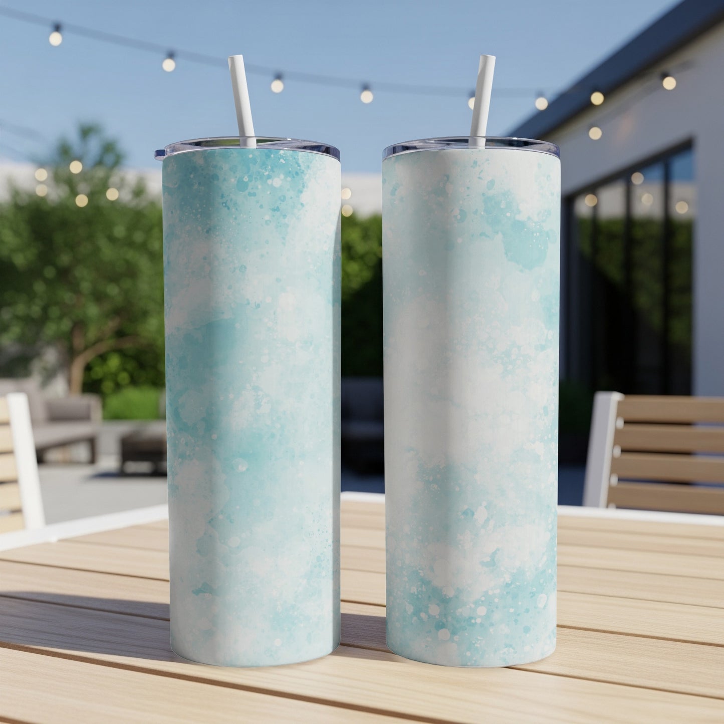Two skinny tumblers with light blue watercolor patterns sit on a wooden table.